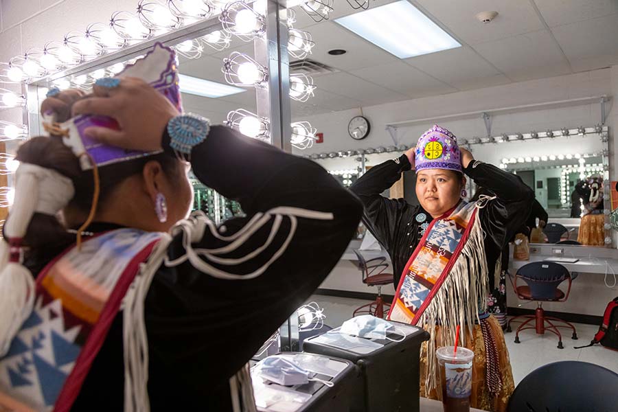 Contestant adjusts traditional regalia and headdress in dressing room before Ms. Indigenous San Juan College cultural pageant