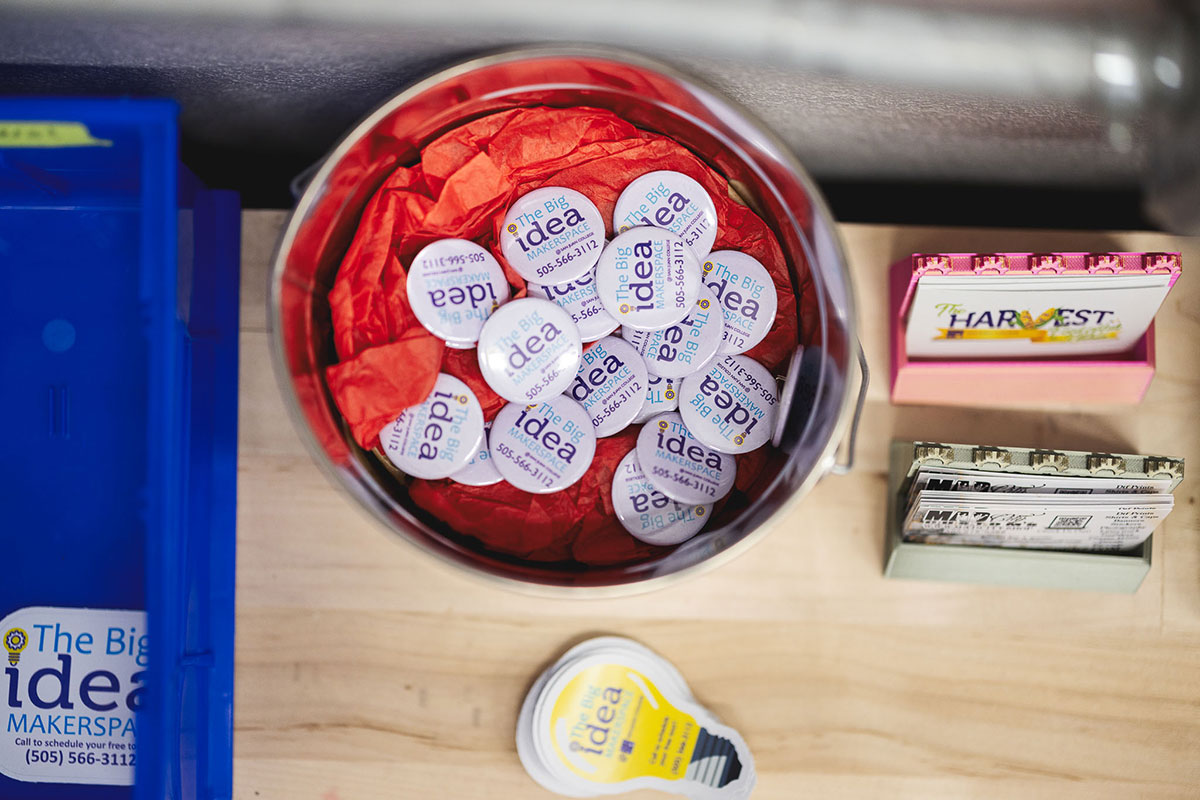 A bucket full of The Big Idea Pins, vinyl cut stickers of lightbulbs reading The Big Idea, business cards